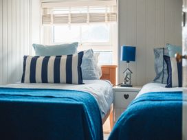 A bedroom with twin beds, lamps and window at Gerallt in Morfa Nefyn