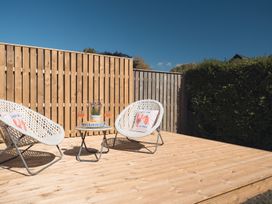 A garden with chairs and a table on a deck at Gerallt in Morfa Nefyn