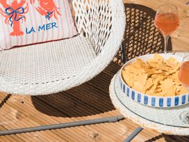 An outdoor area with a chair, a cushion, a table with snacks and drinks at Gerallt in Morfa Nefyn