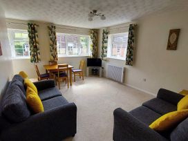 A living room with sofas, a table and a television at West Lulworth Apartment in West Lulworth