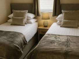 A bedroom with two beds and a lamp at Birch Lodge in Warton near Carnforth