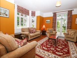 A living room with sofas tables a lamp and patterned curtains at High House in Southrepps