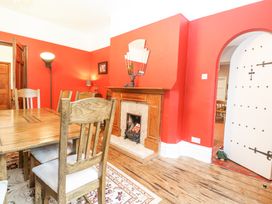 A dining room with wooden table and chairs a fireplace and red walls at High House in Southrepps