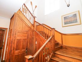 An interior wooden staircase with a door underneath two crossed paddles on the wall a framed picture and antlers above at High House Southrepps