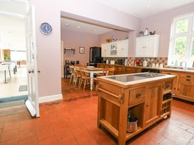 A kitchen with wooden cabinets a kitchen island and a dining table with chairs at High House in Southrepps