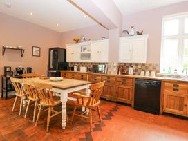 A kitchen with a wooden dining table and chairs wooden cabinets and a black refrigerator at High House in Southrepps