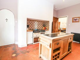 A kitchen with a wooden island and stove with tiled backsplash at High House in Southrepps