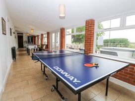 A games room with a ping pong table foosball table and seating near large windows at High House in Southrepps