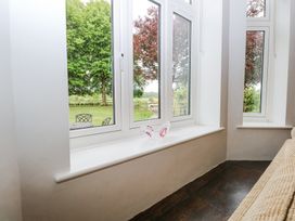 A seating area with a beige sofa near corner windows overlooking a garden at High House in Southrepps