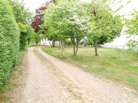 A gravel driveway lined with trees and hedges leading to a house at High House in Southrepps