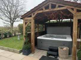 A hot tub under a canopy in a garden at High House in Southrepps