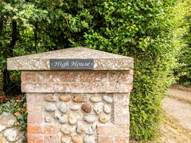 A house sign on a brick pillar surrounded by greenery at High House in Southrepps
