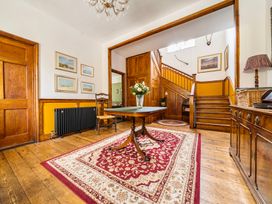 A hallway with a staircase and decorative table at High House in Southrepps