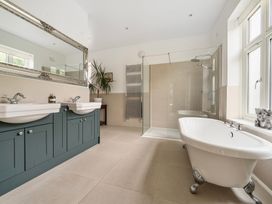 A bathroom with double sinks, a shower, and a free-standing tub at High House in Southrepps