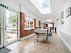A conservatory with a pool table and windows at High House Southrepps