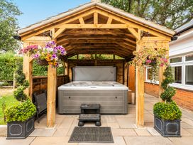 A hot tub under a roof with flowers and planters at High House Southrepps