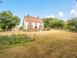A house with a swing set and trees in the garden at High House in Southrepps