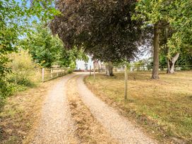 A gravel path leading to a house with trees and a fence at High House in Southrepps