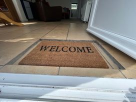 A tiled entryway with a welcome mat recessed into the floor at Min Y Mor in Llanystumdwy near Criccieth