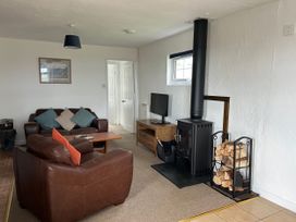 A living room with a sofa and wood stove at Min Y Mor Llanystumdwy near Criccieth