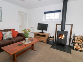 A living room with a sofa, TV, and wood stove at Min Y Mor Llanystumdwy near Criccieth