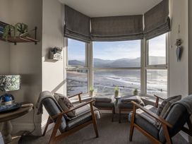 A sitting area with two armchairs facing a large bay window overlooking a beach and mountains at Harbour View Flat 2 in Barmouth