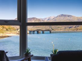 A window view of a body of water with a bridge and mountains in the background at Harbour View - Flat 2 in Barmouth