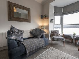 A sitting area with a sofa chair cushions and a lamp by a window with a view at Harbour View - Flat 2 in Barmouth