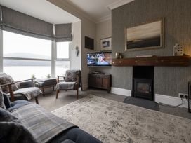 A living room with two armchairs a sofa a wall-mounted television and a fireplace at Harbour View - Flat 2 in Barmouth