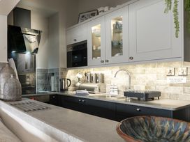 A kitchen with black and white cabinets a countertop with a kettle and sink at Harbour View - Flat 2 in Barmouth