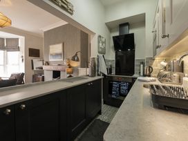 A kitchen with black cabinets and appliances next to a living room with a fireplace at Harbour View - Flat 2 in Barmouth