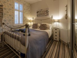 A bedroom with a metal bed frame striped carpet and two bedside tables with lamps at Harbour View - Flat 2 in Barmouth