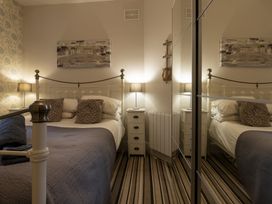 A bedroom with a bed pillows bedside tables lamps and a mirrored wardrobe at Harbour View - Flat 2 in Barmouth