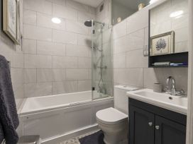 A bathroom with a bathtub shower toilet sink and a mirror cabinet at Harbour View - Flat 2 in Barmouth