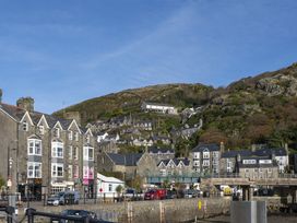 Stone buildings and hillside houses near a waterfront with a road and vehicles at Harbour View Flat 2 in Barmouth