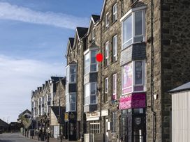 A street with stone buildings housing shops and restaurants under a blue sky at Harbour View - Flat 2 in Barmouth