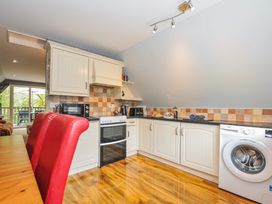 A kitchen with appliances and seating at Hideaway Cottage St Ann's Chapel, Cornwall