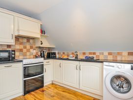 A kitchen with cabinets, oven, microwave and washing machine at Hideaway Cottage St Ann's Chapel, Cornwall