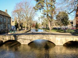 A bridge over a river with trees and buildings at Mallards in Bourton-On-The-Water