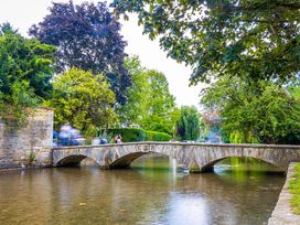 A bridge over a river with trees and people at Mallards in Bourton-On-The-Water