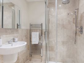A bathroom featuring a shower, sink, and towel radiator at Middle Dean Farmhouse in Trentishoe near Parracombe