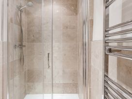 A shower with glass enclosure and towel rail at Middle Dean Farmhouse Trentishoe near Parracombe