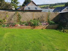 A garden with a flower bed and fence at Middle Dean Farmhouse in Trentishoe near Parracombe