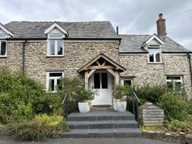 A stone house with a wooden front door and steps at Middle Dean Farmhouse Trentishoe near Parracombe
