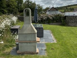 A garden with a chimney and table at Middle Dean Farmhouse Trentishoe near Parracombe