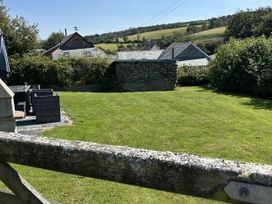 A garden with a stone wall and patio furniture at Middle Dean Farmhouse Trentishoe near Parracombe