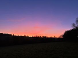 A sunset over a field with trees at Middle Dean Farmhouse near Parracombe