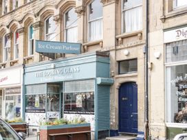 A street view showing an ice cream parlour called The Looking Glass with a blue door next to it at Gerrard House Apartment in Llandudno