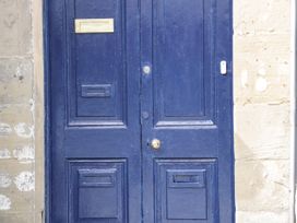 A blue double door with a mail slot and doorbell on a stone wall at Gerrard House Apartment in Llandudno