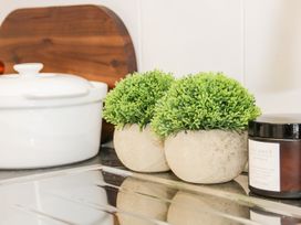 Two small round potted plants next to a white pot and a jar on a kitchen counter at Gerrard House Apartment in Llandudno